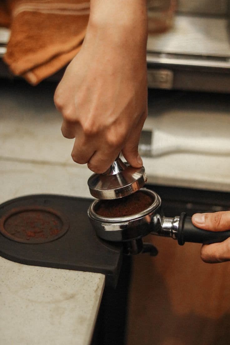 A barista tamping ground coffee into a portafilter.